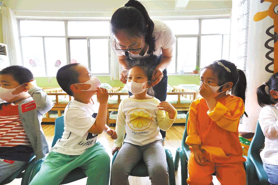 近日,在东港区日照街道幼儿园,老师正在帮小朋友体验儿童口罩.